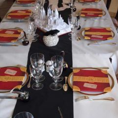 Table harmonie de blanc, noir et rouge, composée d'une nappe blanche, d'un chemin de table noir, de portes- serviette rouges imitation livre, d'encrier en guise de boîte à bonbons et d'un centre de table en forme de livre ouvert avec château façon pop-up.