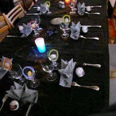 Table composée d'une nappe noir, d'un chemin de table noir peint comme un ciel étoilé, de serviettes grises en forme d'étoiles, de chevalets en forme de casques de cosmonautes.